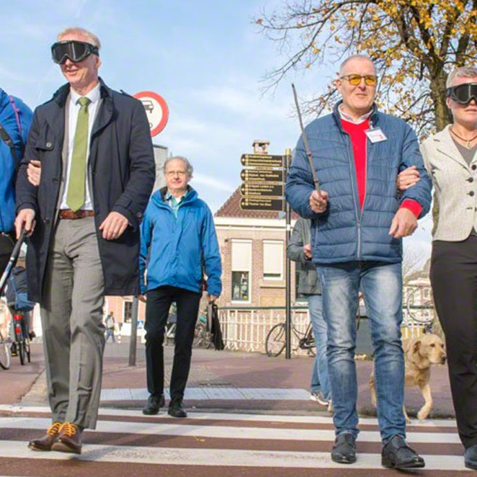 Foto van blinden en slechtzienden die oversteken met hulpmiddelen